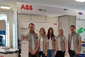 Young employees standing next to the event stand with ABB logos on their jackets