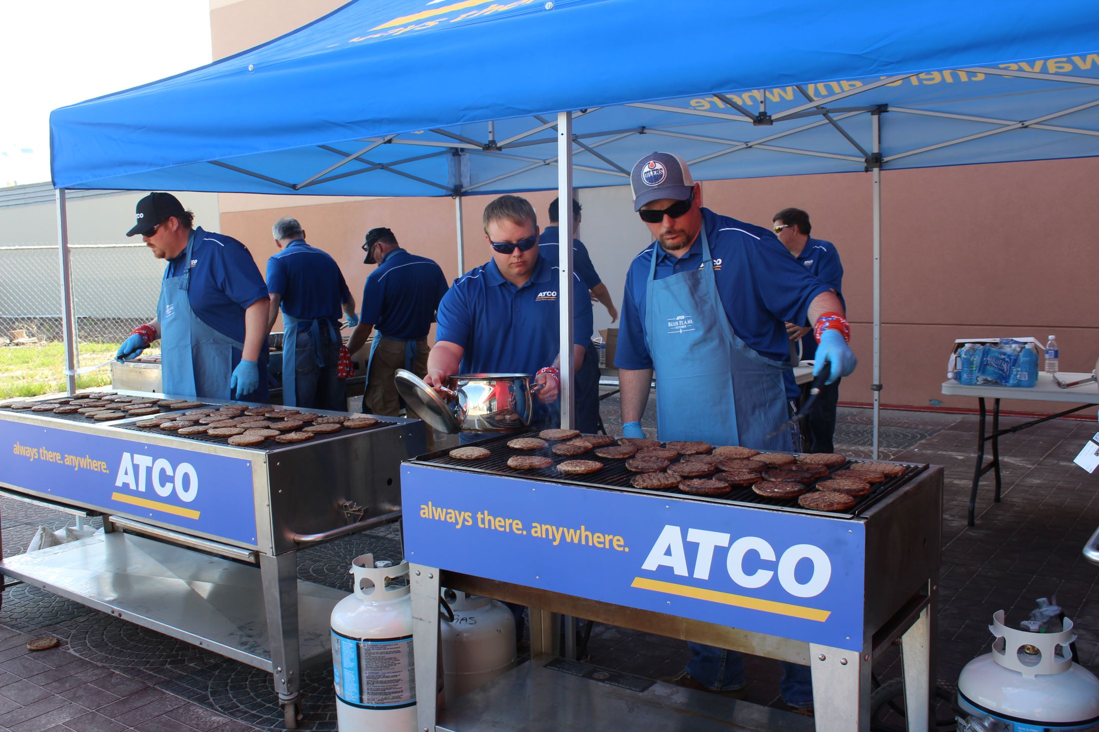 ATCO employees serve up hamburgers at a community barbeque event. 