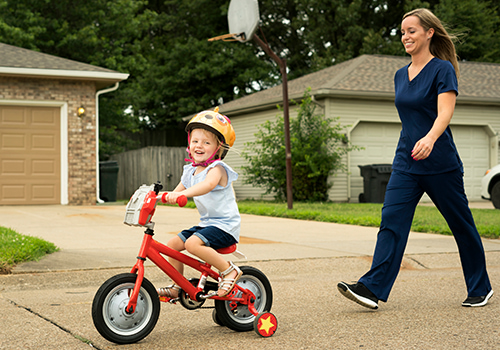 Tile - Ascension - Explore PRN opportunities - Nurse walking behind daughter as she rides a bike
