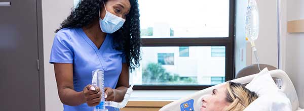 Tile - Ascension Allied Health Respiratory Therapy - Female nurse aiding patient in hospital bed