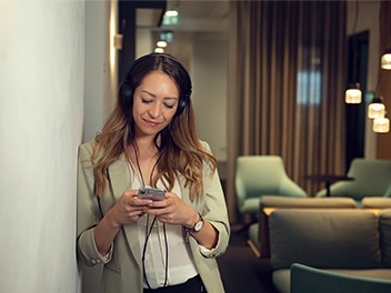 Woman leaning against the wall and looking into her cell phone