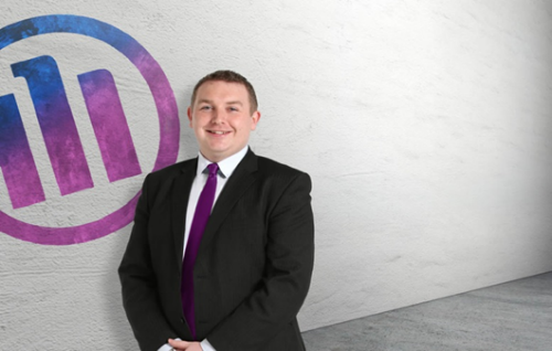 Allianz employee smiling in front of the Allianz logo.