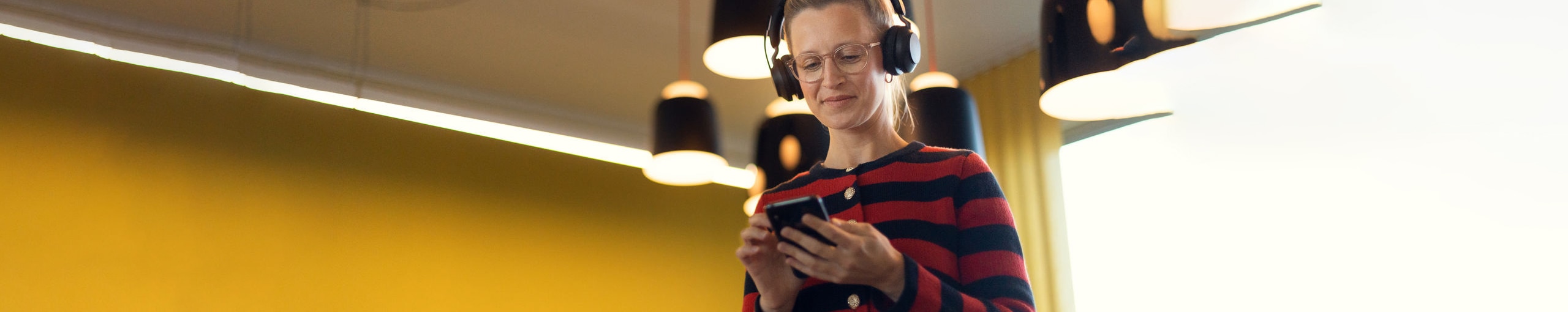 Young colleague wearing a headset, scrolling through their phone