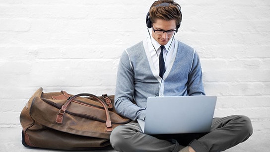 Allianz employee sits on the ground, working with his laptop and headphones