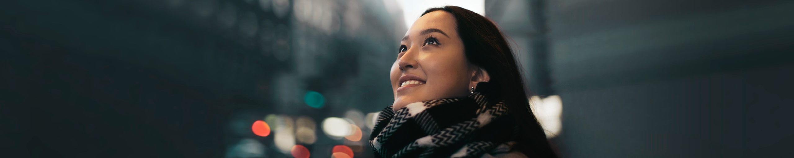 A happy woman with a scarf around her neck, looking forward.
