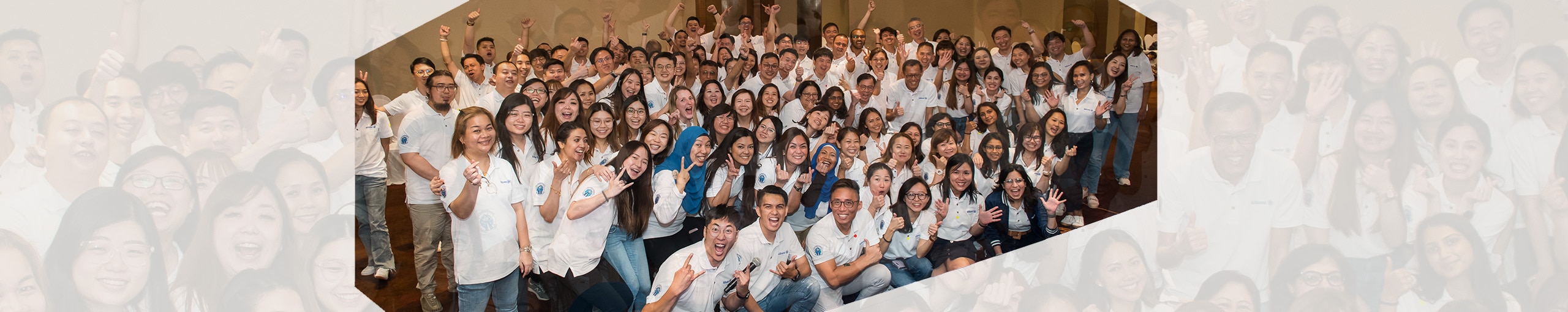 Group of employees celebrating together with a 'win' sign, smiling and posing for the photo.