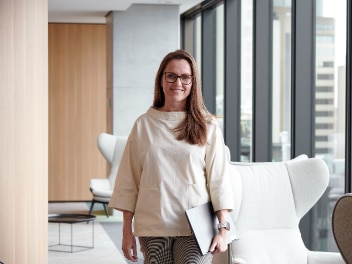 Allianz employee laughing and walking around with her laptop in an office building