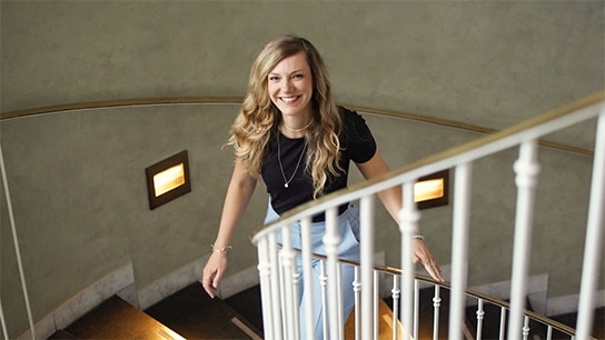 Lana, an Allianz employee walking up the stairs ans smiling