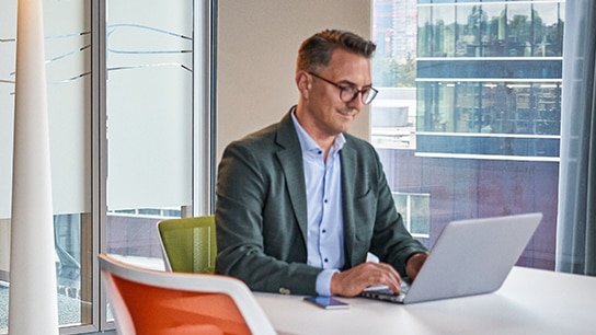Un employé souriant travaille sur son ordinateur portable