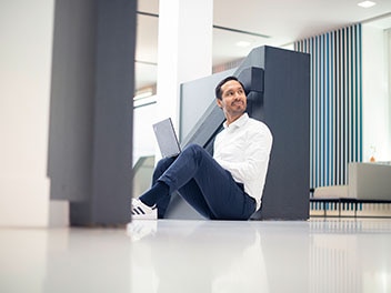 Un employé d'Allianz assis par terre avec son ordinateur portable