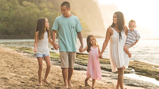 Familiy walking at the beach hand in hand wearing summer clothes