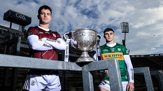 two men standing next to a trophy in a stadium