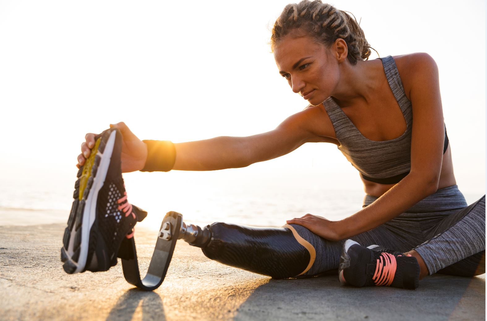 women is streching on the ground wearing a grey sports outfit