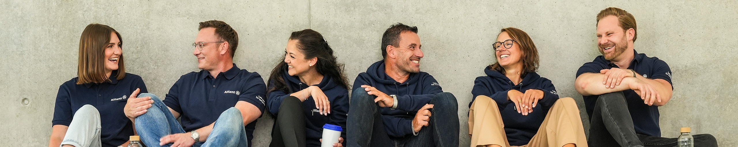Mitarbeiter der Allianz sitzen auf dem Boden und unterhalten sich und lachen