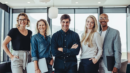 Allianz Mitarbeiter stehen in einem Bürogebäude zusammen und lachen