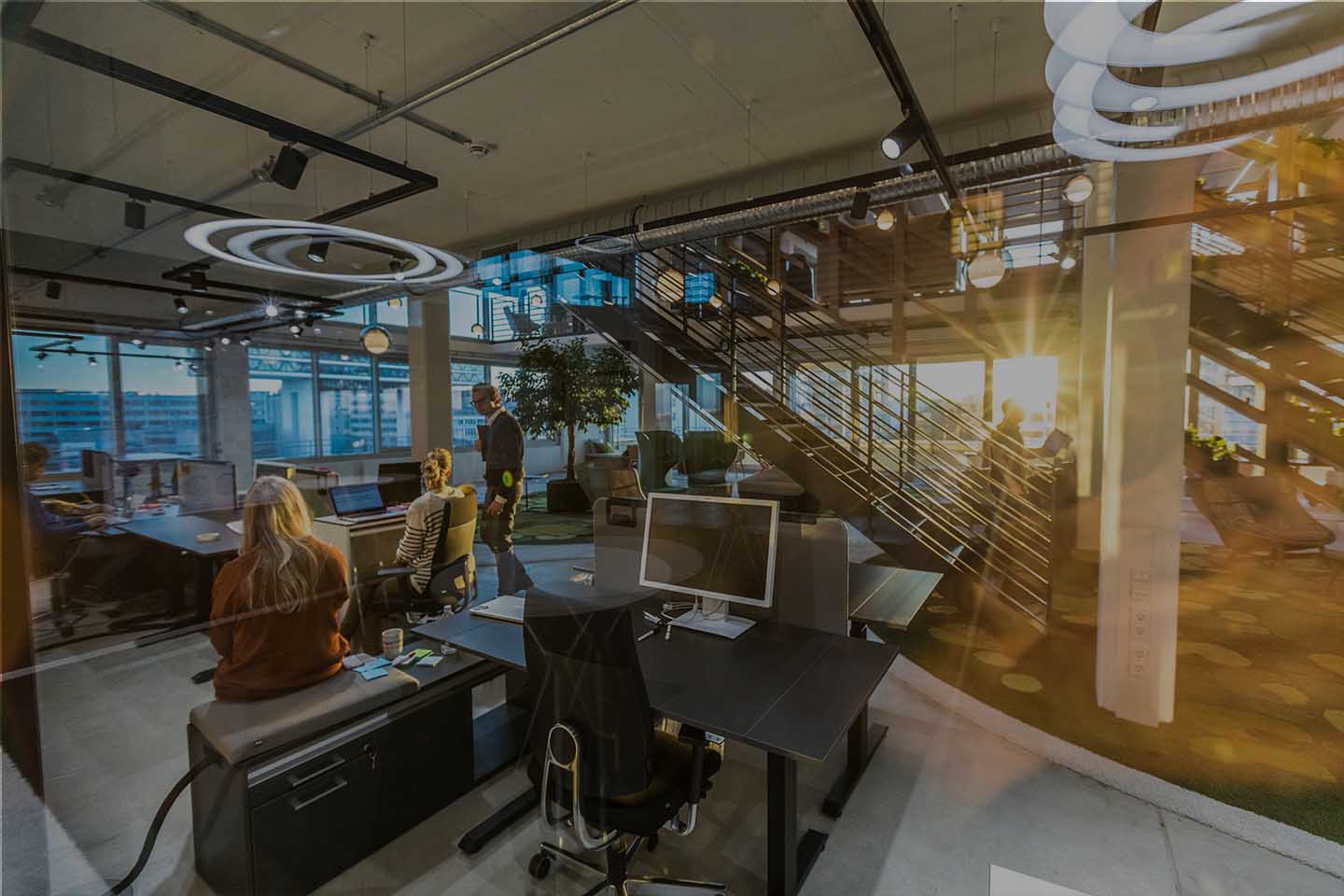 Büroraum in welchem einige Mitarbeiter am arbeiten sind, viele Computer und Büroeinrichtungen