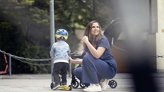 Una madre sorridente si inginocchia davanti al suo bambino