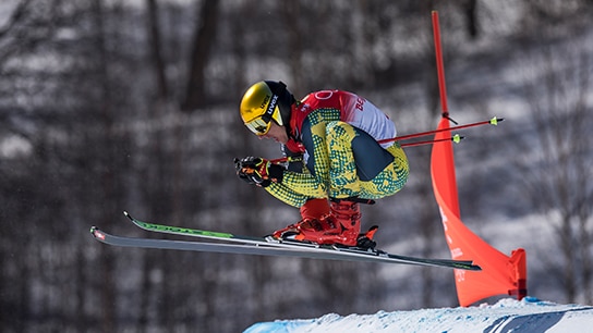Skifahrer springt in Skiausrüstung über die Skipiste.