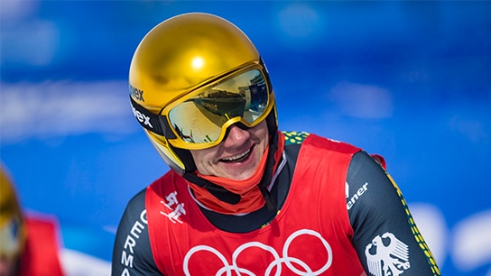 Skifahrer in Skikleidung mit goldenem Helm am lächeln