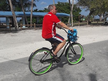 Mann fährt Fahrrad vor einer grünen Landschaft