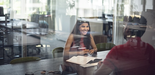 Zwei Allianz Mitarbeitende sitzen sich in einem Meetingraum gegenüber