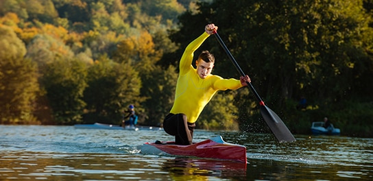 Sportler paddelt mit Kayak über den Fluss