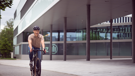 Fahradfahrer mit Helm vor einem Allianzgebäude