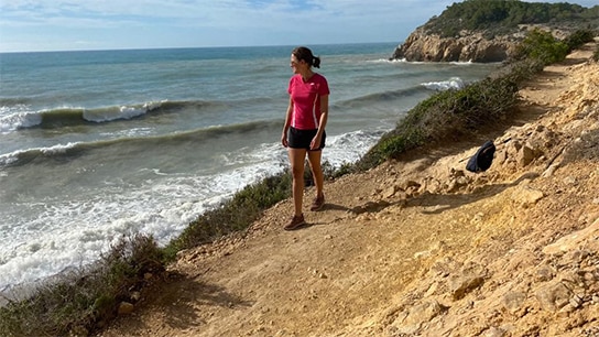 Frau in Sportklamotten bei einer Wanderung am Meer