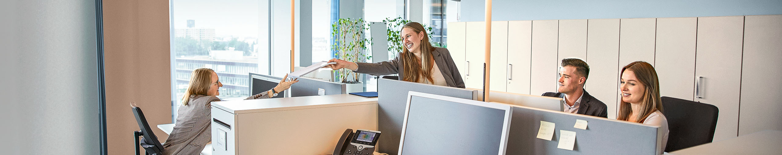 Lächelnde Allianz Kollegin übergibt ein Dokument im Büro