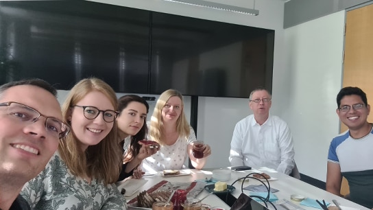 Team sitzt gemeinsam an einem Besprechungstisch und frühstückt
