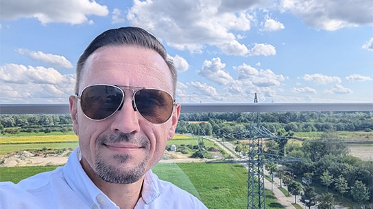 Mann mit Sonnenbrille vor grüner Landschaft