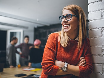 happy employee laughing in an office setting, with colleagues visible in the background, creating a lively and positive work atmosphere