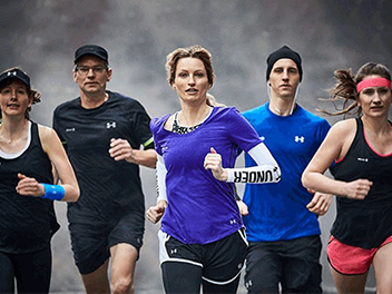 Five people running in sports outfits, actively engaged in a race