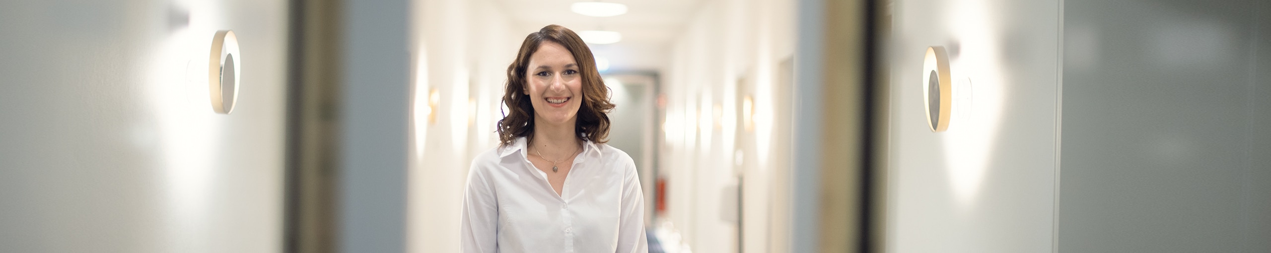 An employee standing in a corridor with a smiling expression
