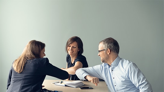 Three colleagues celebrating with an elbow bump