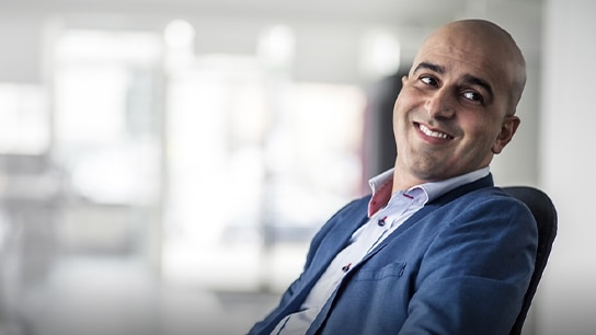 Um profissional feliz, reclinado em uma cadeira, olhando de soslaio.