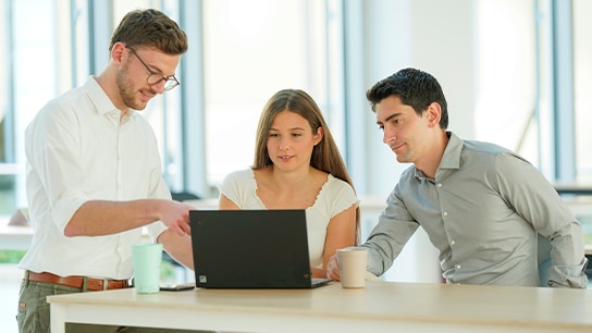 Gruppe von Mitarbeitenden am Laptop