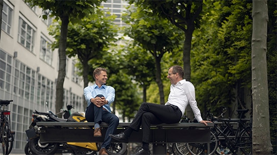 happy colleagues relaxing and engaging in a joyful conversation while sitting on a bench outside the workplace