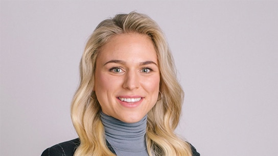Blonde Frau lächelt und hat einen grauen Rollkragenpullover an