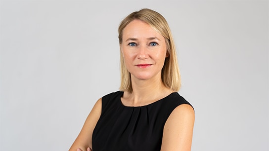 Frau in schwarzem Oberteil vor einer weißen Wand