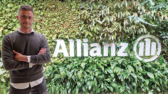 Mann steht vor einer Grünen Wand mit Allianz Logo