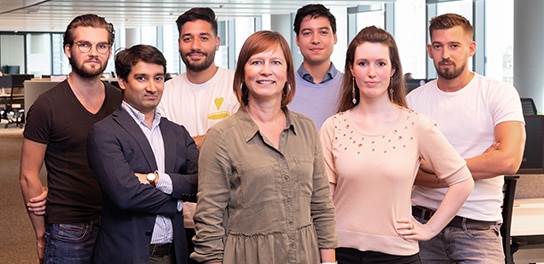 Sept collègues d'Allianz se tiennent dans un bureau et regardent la caméra.