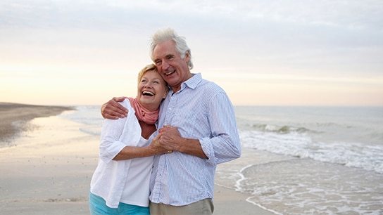 Twee oude mensen lachen op het strand