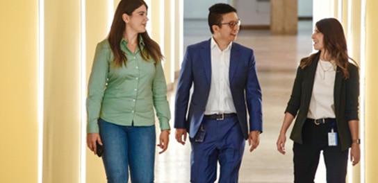 Trois collègues marchent dans un couloir et discutent.