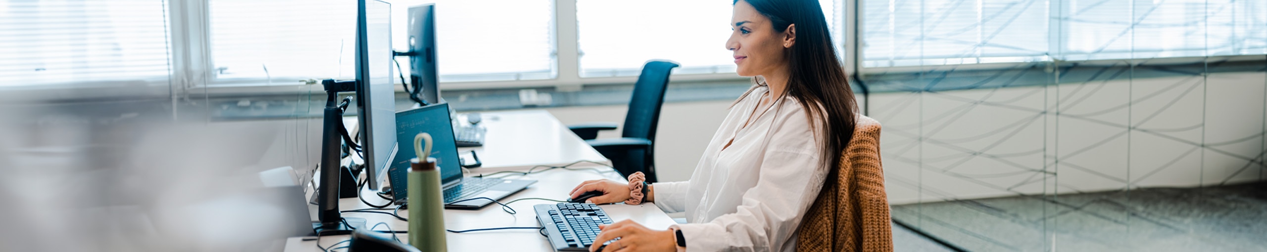 Vrouw zit achter de computer en ziet er gelukkig uit