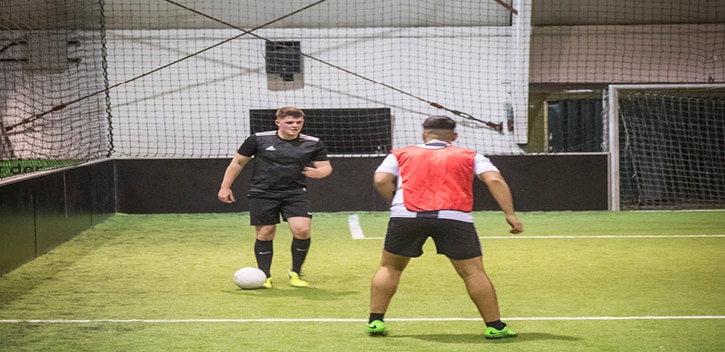 Zwei Männer in einer Sporthalle beim Fussball spielen