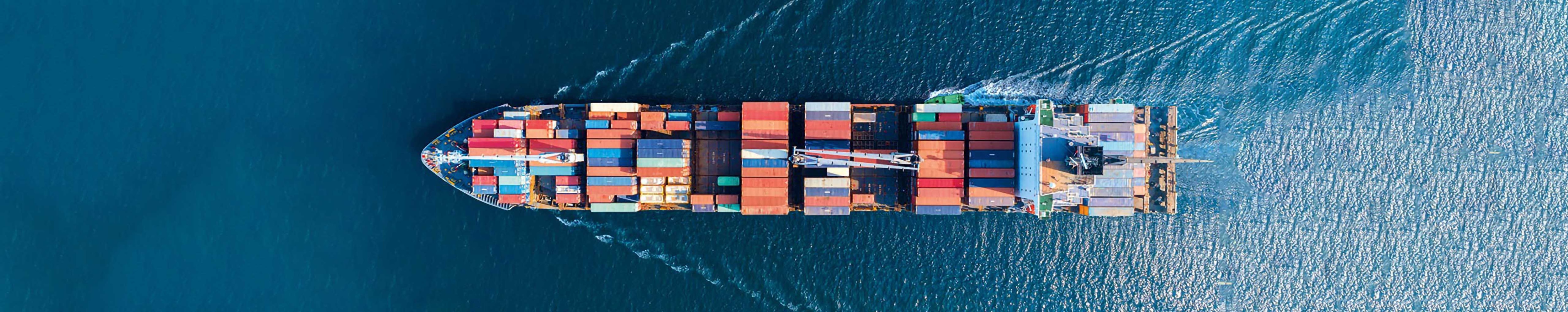 Aerial top view of cargo maritime ship with contrail in the ocean ship carrying container