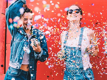 Two young women throwing paper confetti