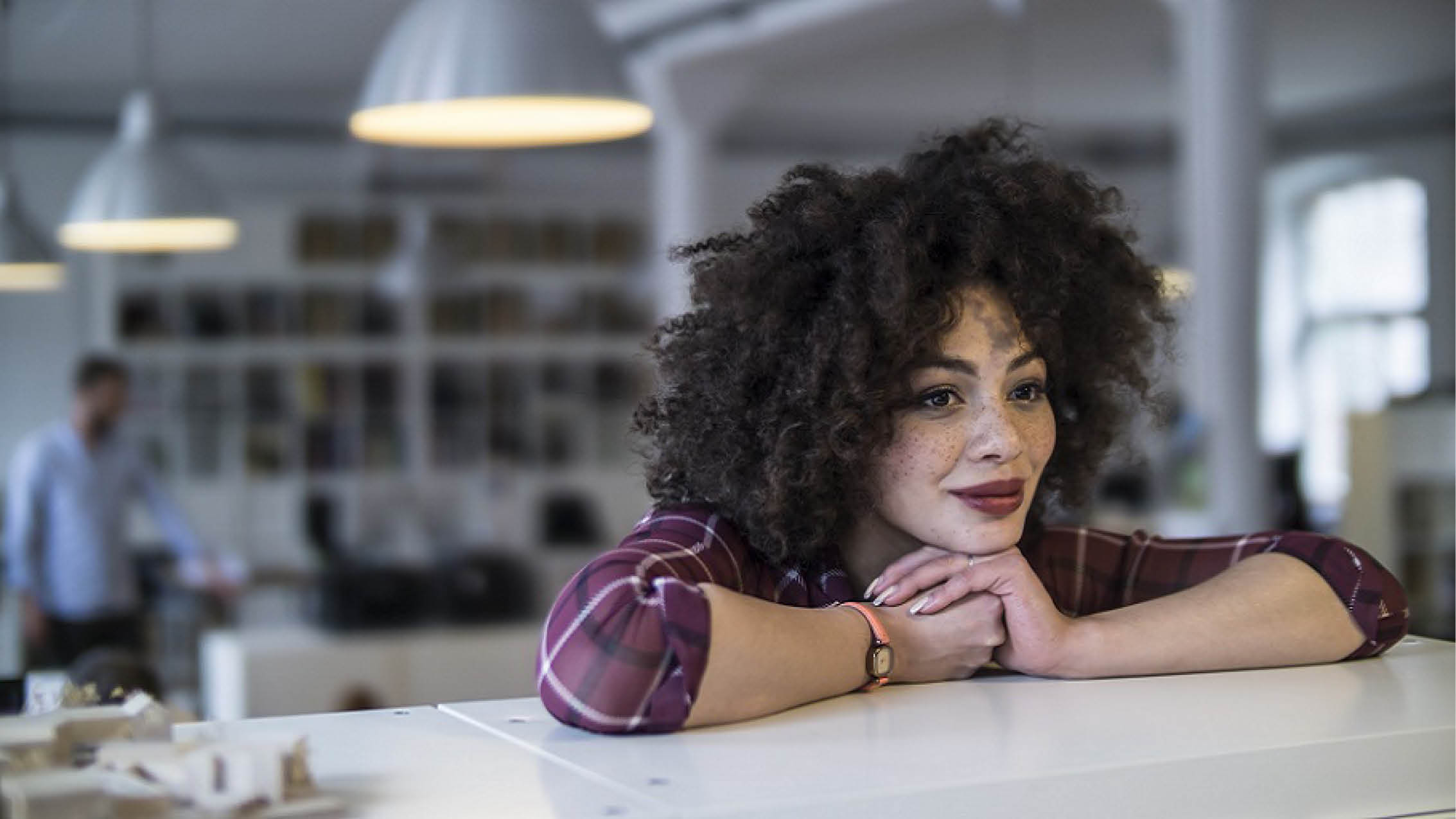 Frau lehnt auf einem Regal in einem Büroraum