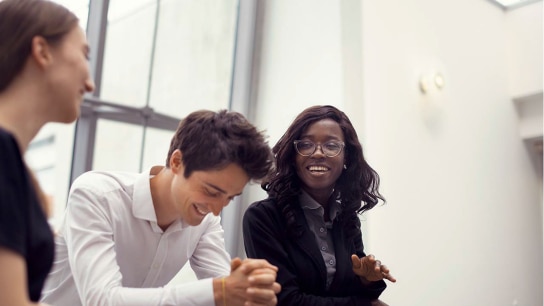Three employees in a joyful conversation showcasing diversity